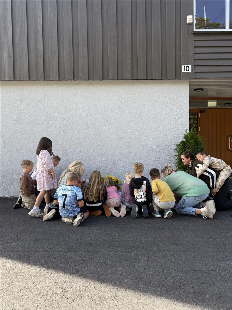 Barn som sitter rundt blomster og hilsner - Klikk for stort bilde