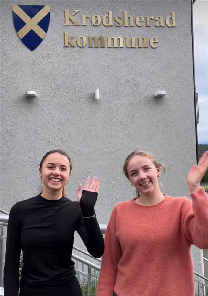 To jenter som vinker foran Krødsherad kommunehus - Klikk for stort bilde