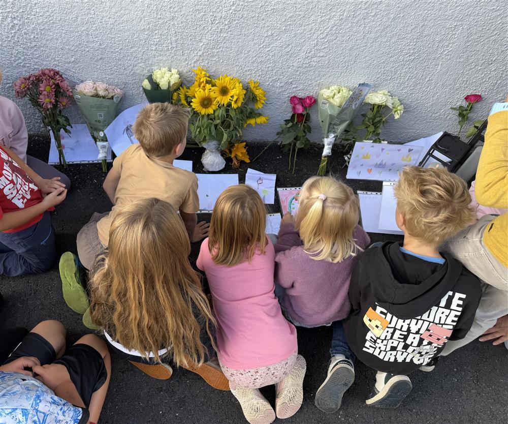 Barn som sitter rundt blomster og hilsner - Klikk for stort bilde