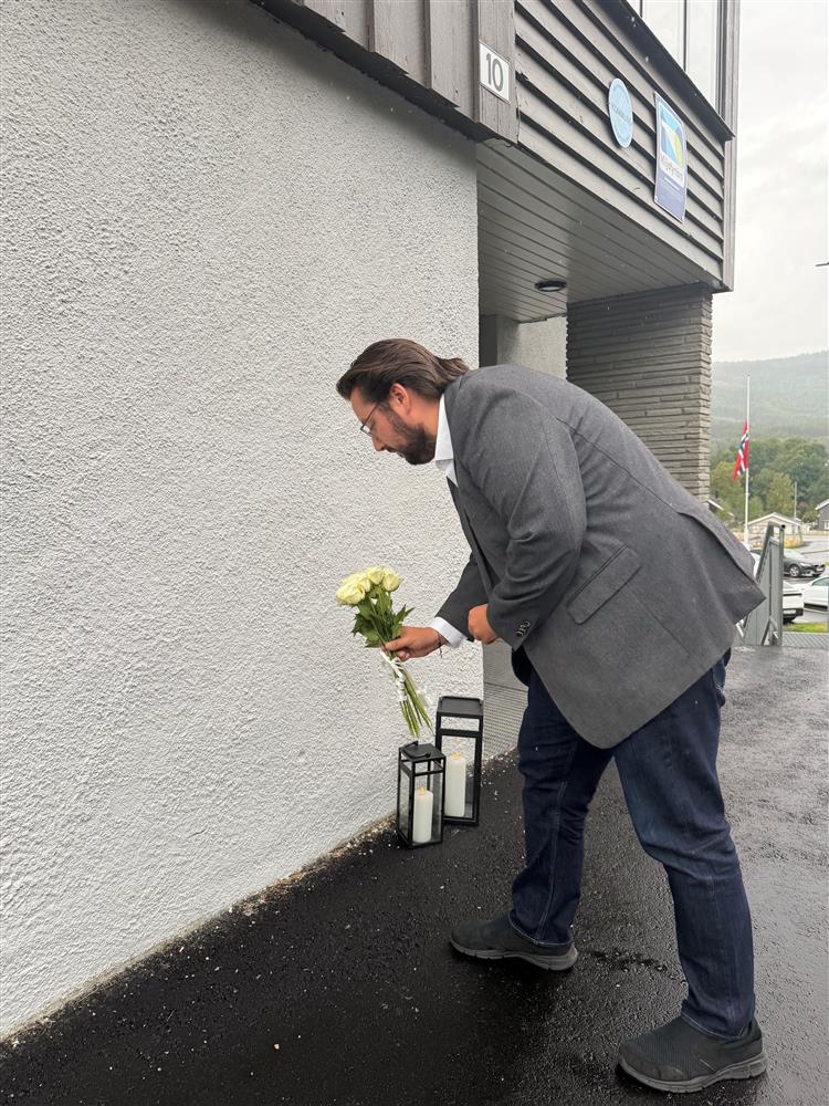 En mann som legger ned blomster ved inngangen til kommunehuset - Klikk for stort bilde